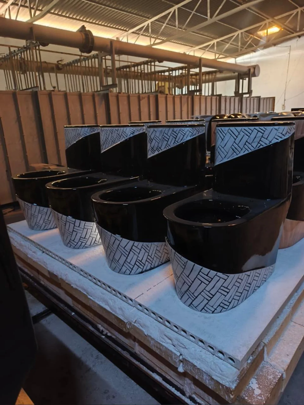 Black and patterned one-piece toilets on a kiln car